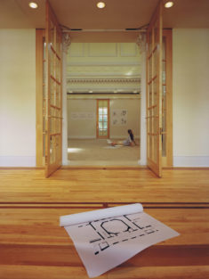 A view through the front entry into the rotunda showing a student looking at drawings pinned to the wall.